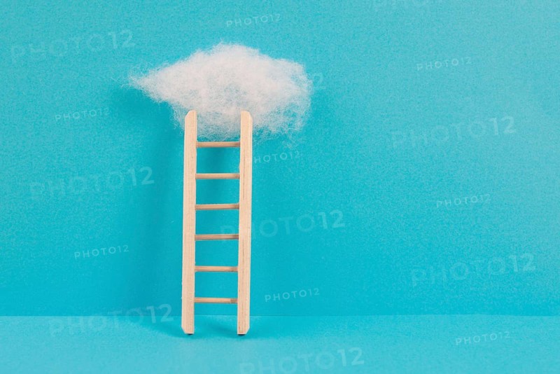 Ladder with a cloud on top, blue colored background, copy space, dreaming of success, creative and business concept, achieving new goals