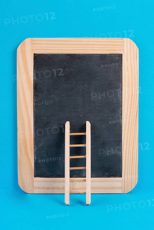 Ladder on an empty chalkboard, blue colored background, copy space, education, success, creative and business concept, achieving new goals