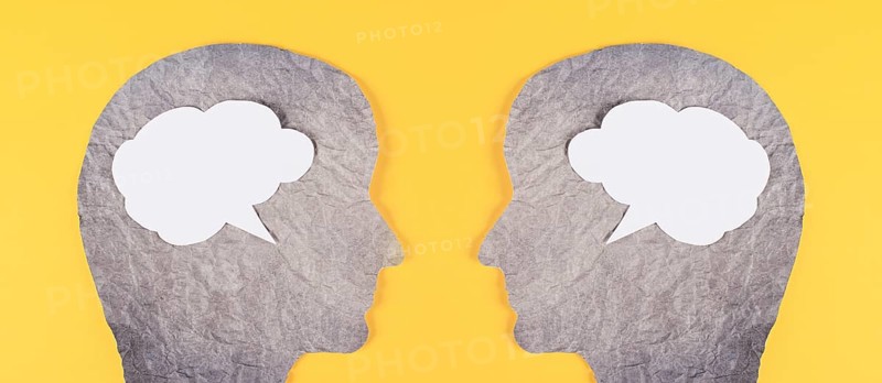 Silhouette of two faces, speech bubble in white color, copy space for text, communication, having an opinion and discussion, free speech, people talking, yellow background