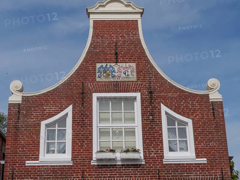 A facade of a historic building with red brick walls and white window frames, Greetsiel, East Frisia, Lower Saxony, Germany, Europe