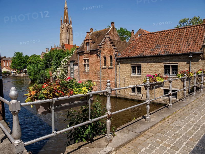 Picturesque bridge with flowers, historic buildings and church tower, sunny summer atmosphere by the river, Bruges, Flanders, Belgium, Europe