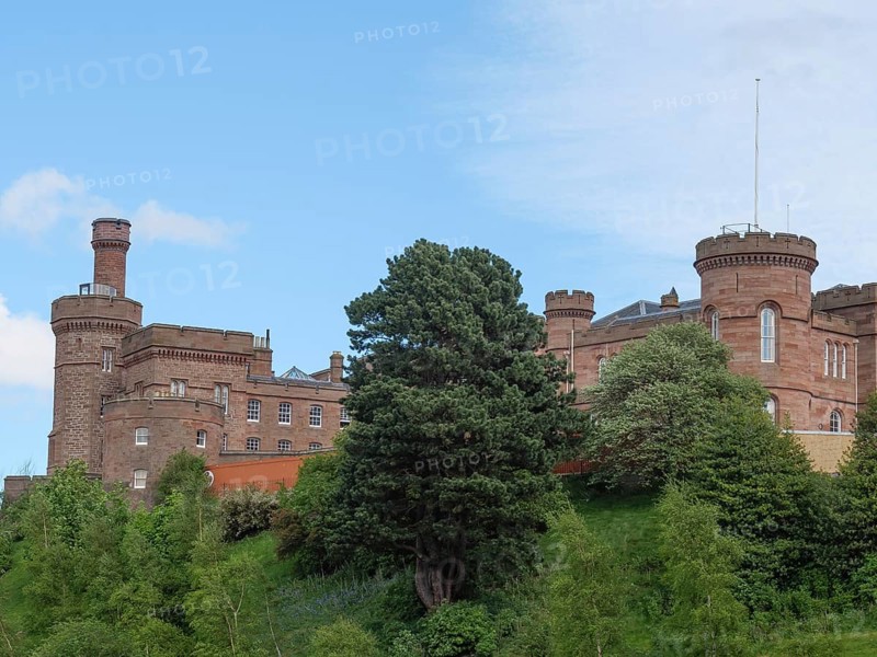 A large castle on a green hill, surrounded by trees and under a blue sky, inverness, scotland, Great Britain