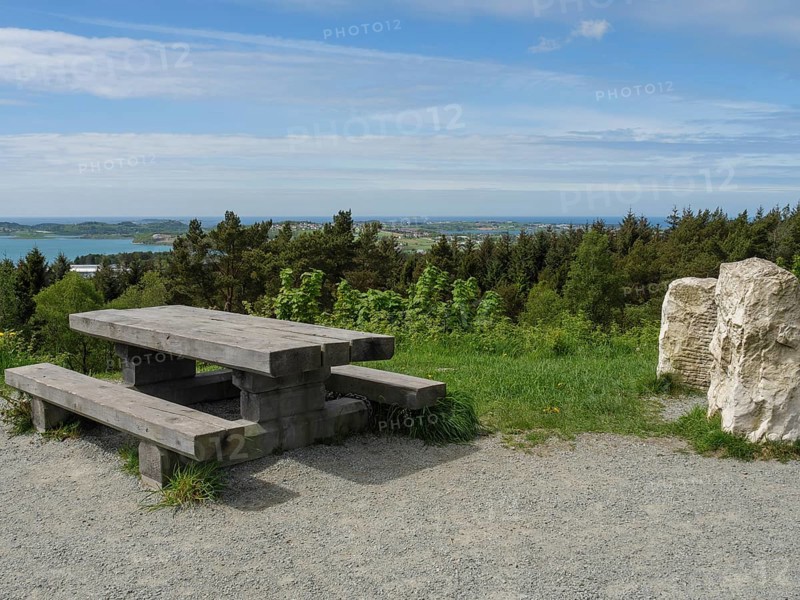 Wooden table and bench on a gravel path with a view of the forest and sea under a slightly cloudy sky, Stavanger, Norway, Scandinavia, Europe