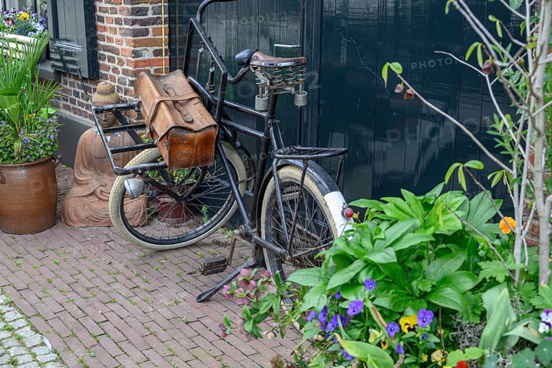 Old bicycle with bags in a cosy alley with many plants and flower pots, Bredevoort, gelderlande, the netherlands