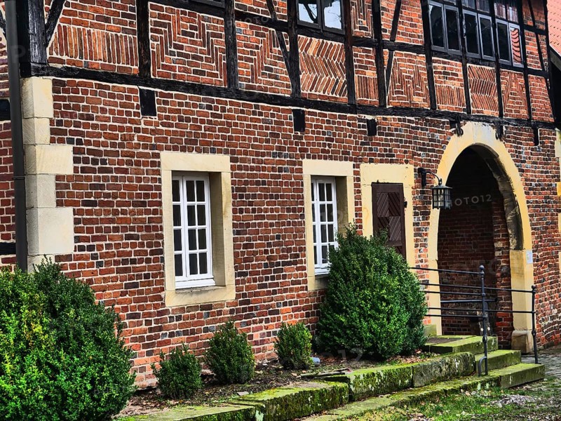 The entrance of a half-timbered house with brick walls, white windows and green bushes, asbeck, legden, Münsterland, North Rhine-Westphalia, Germany, Europe