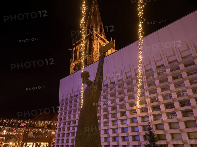 Statue in front of an illuminated church at night with fairy lights creating a festive atmosphere, Ahaus, Münsterland, North Rhine-Westphalia, Germany, Europe