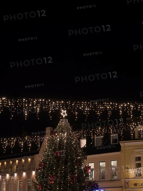 Large Christmas tree with festive lights and star on top, surrounded by illuminated buildings at night, Ahaus, Münsterland, North Rhine-Westphalia, Germany, Europe