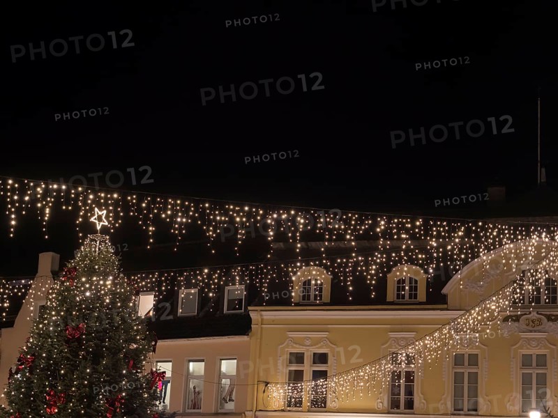 Festively illuminated Christmas tree and buildings on a dark night. Fairy lights hang over the scenery and create a festive atmosphere, Ahaus, Münsterland, North Rhine-Westphalia, Germany, Europe