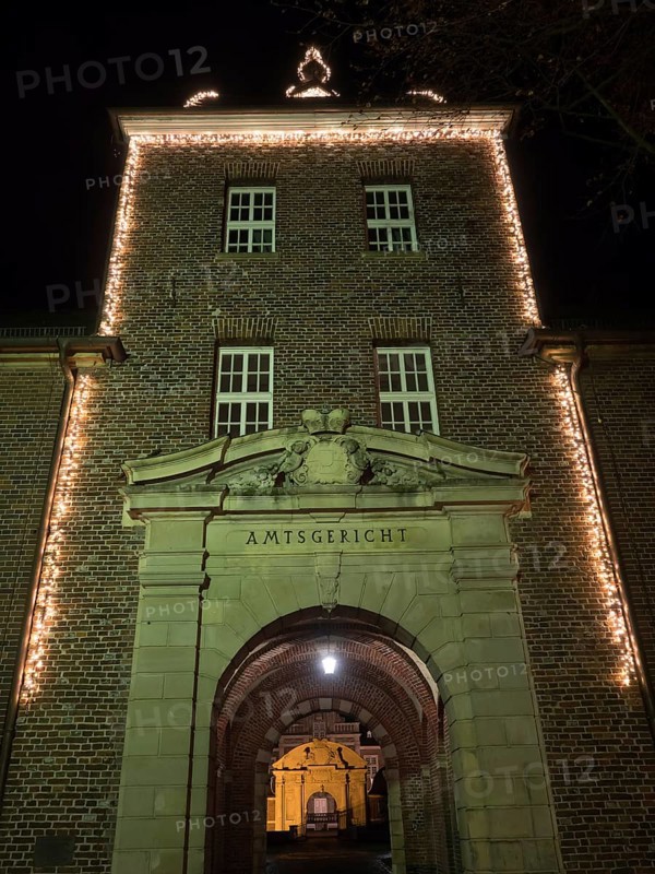 Brick entrance area of a district court with illuminated arch and fairy lights at night, Ahaus, Münsterland, North Rhine-Westphalia, Germany, Europe