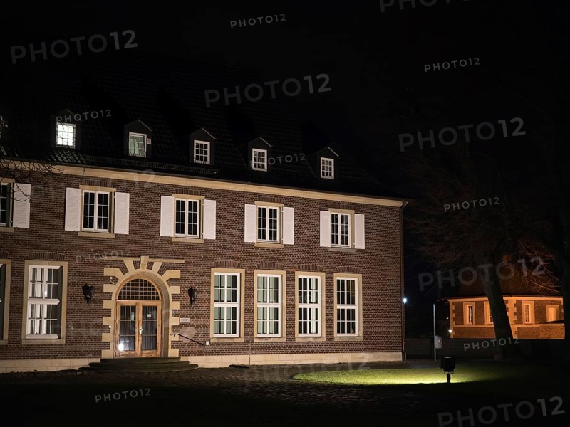 A large historic building illuminated at night, with many windows and a small lawn in front of it, Ahaus, Münsterland, North Rhine-Westphalia, Germany, Europe
