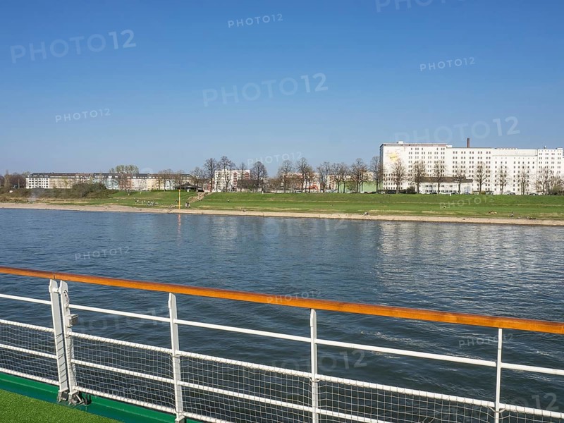 View from a ship's railing onto a river and apartment blocks in an urban environment, Cologne, North Rhine-Westphalia, Germany, Europe