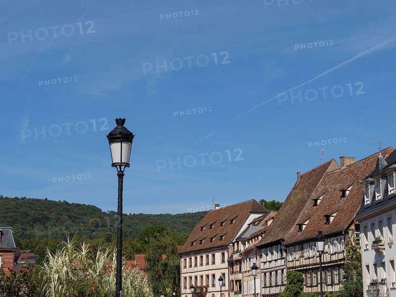 Street lamp in front of a row of traditional houses with green hills in the background, Wissembourg, Alsace, France, Europe