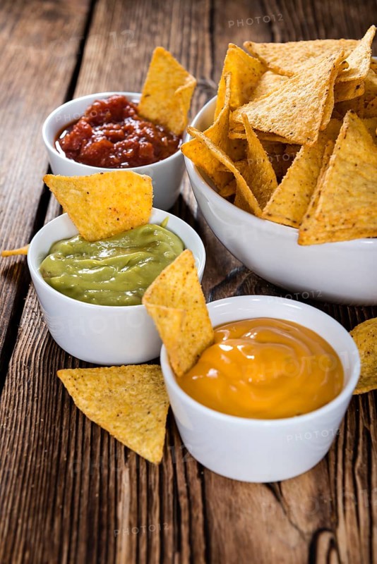 Three different nacho dips (Salsa, Cheese and Guacamole)