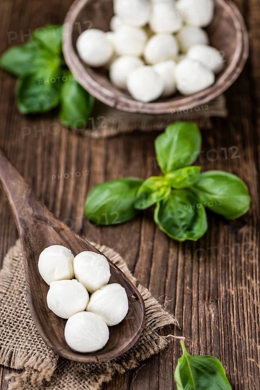 Small Mozzarella balls (on wooden background, selective focus) as close-up shot