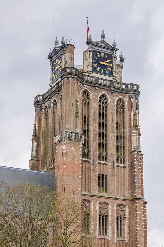 Close-up of a gothic church tower with clocks and a weather vane, dominating the cityscape, Dordrecht, holland, netherlands