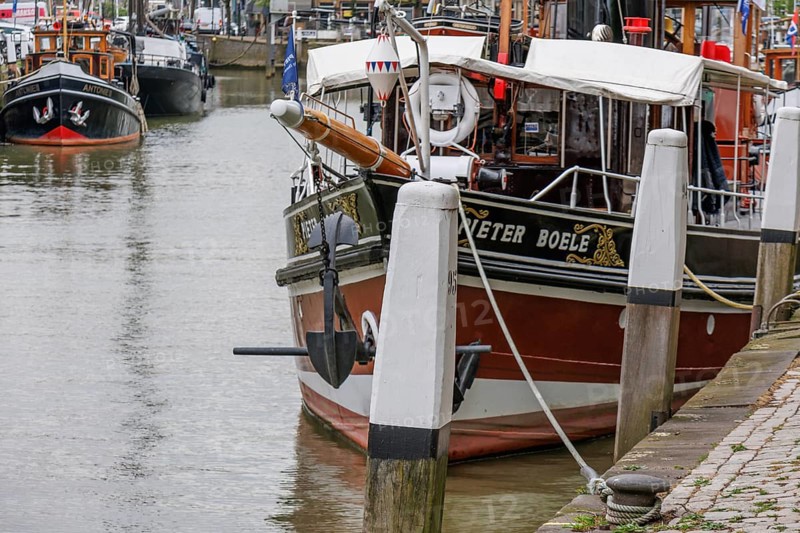 Detailed boat in the harbour, moored to pillars with anchor and white ropes in the foreground, Dordrecht, holland, netherlands