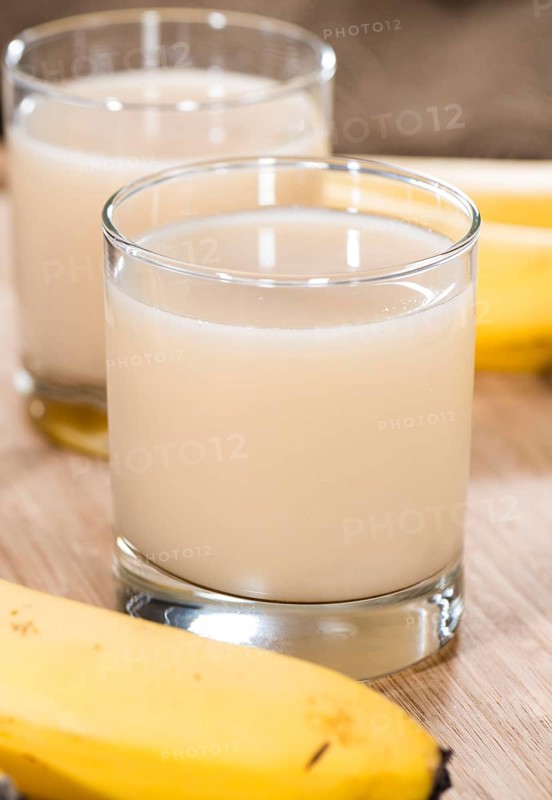 Fresh Banana Juice in a glass (detailed close-up shot) on wooden background