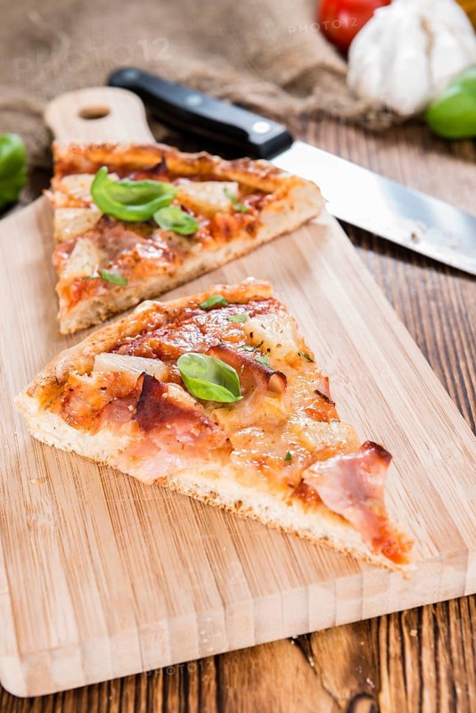 Fresh made Ham and Pineapple Pizza slices (close-up shot)