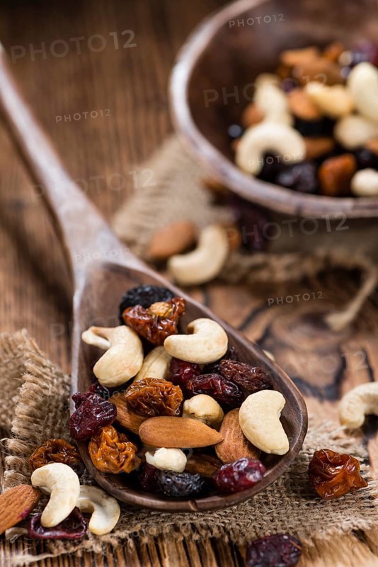 Portion of mixed nuts and fruits (trail mix) on wooden background