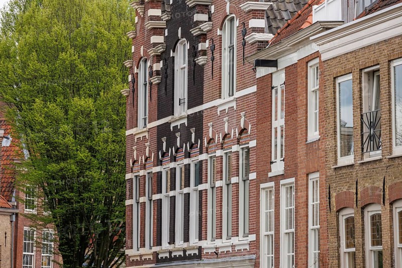 A group of historic brick buildings with detailed facades and trees in the background, Dordrecht, holland, netherlands