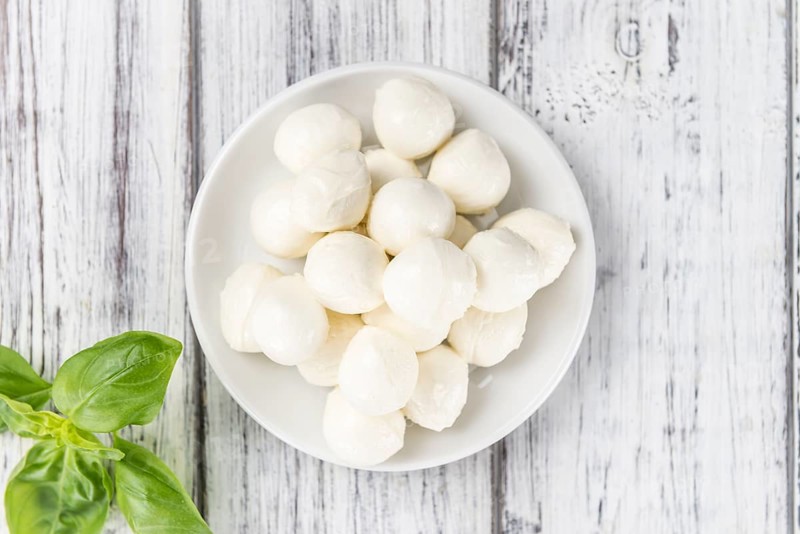 Small Mozzarella balls (on wooden background, selective focus) as close-up shot
