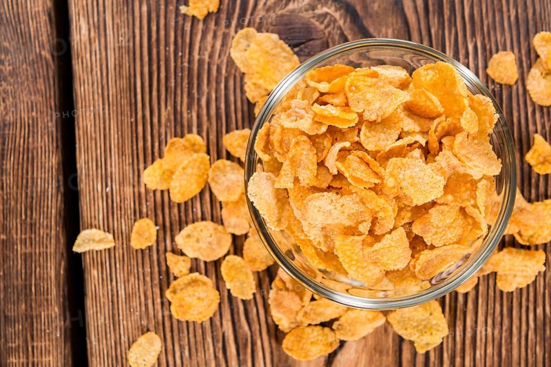 Portion of golden Cornflakes on wooden background (close-up shot)