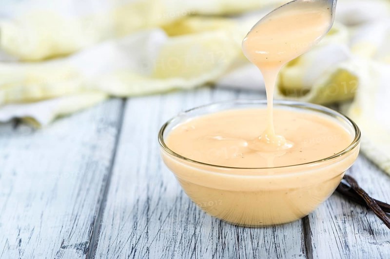 Vanilla Sauce in a small bowl (close-up shot) on wooden background