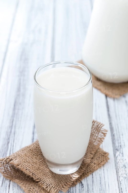 Portion of Milk on bright wooden background (close-up shot)