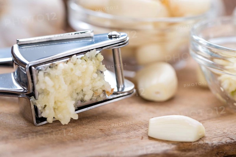 Portion of Crushed Garlic (close-up shot) on wooden background