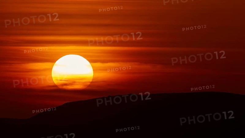 The setting sun breaks through dramatic layers of cloud and illuminates the silhouette of a hill, offshore island, Kritinia Castle, St John's Castle, Kritinia, Rhodes, Dodecanese, Greek Islands, Greece, Europe