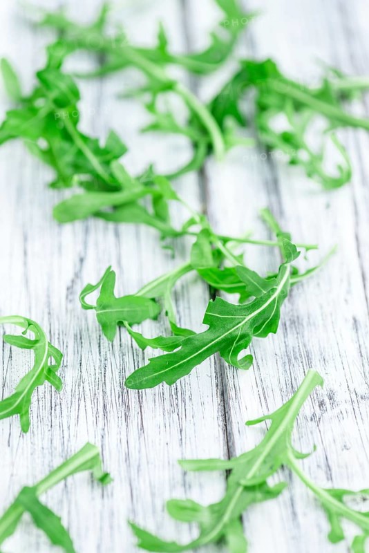Fresh Arugula (selective focus) as detailed close-up shot on vintage background
