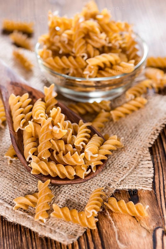 Portion of uncooked Wholemeal Fussili on wooden background