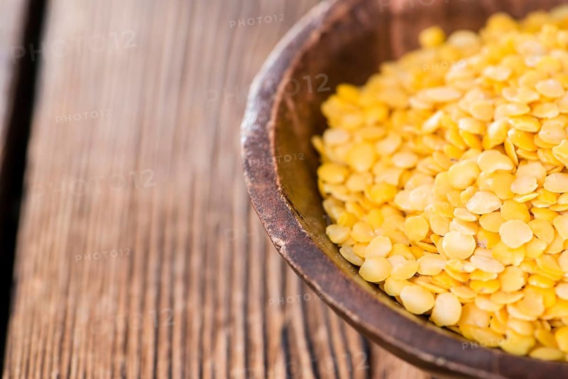 Yellow Lentils (detailed close-up shot) on wooden background