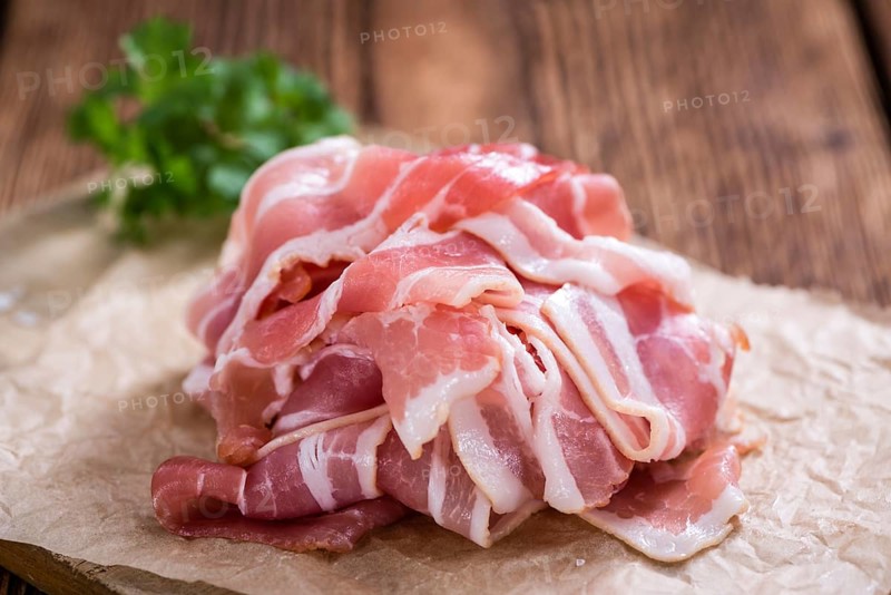Raw Bacon slices (detailed close-up shot) on vintage wooden background