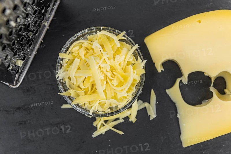 Homemade Grated Cheese (close-up shot) on a vintage slate slab