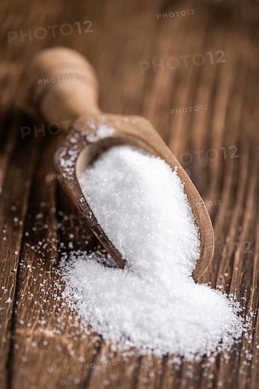 Portion of White Sugar (detailed close-up shot, selective focus) on wooden background