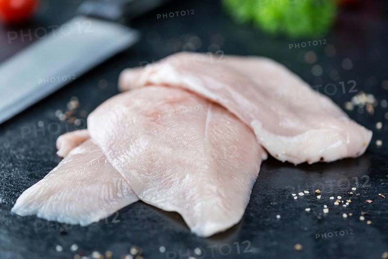 Slate slab with raw Chicken Cutlet (close-up shot)