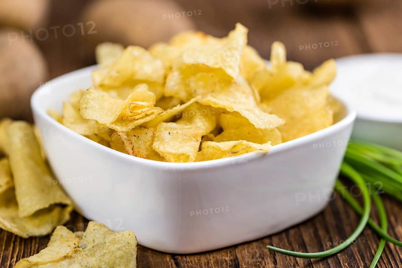 Potato Chips with Sour Cream taste as high detailed close-up shot on a vintage wooden table (selective focus)