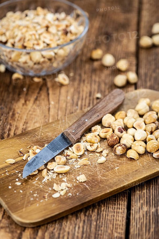 Portion of freshly chopped Hazelnuts on an old wooden table as detailed close up shot (selective focus)