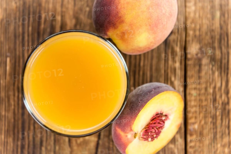 Portion of Peach juice (fresh made) on an old wooden table (close-up shot)