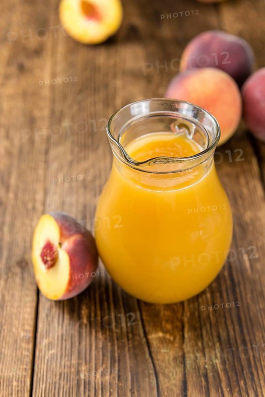 Portion of Peach juice (fresh made) on an old wooden table (close-up shot)