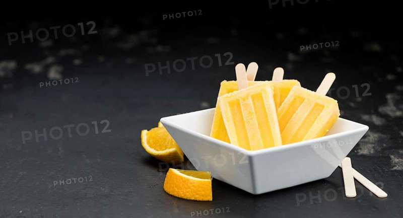 Some homemade orange popsicles on a vintage background (selective focus, close-up shot)