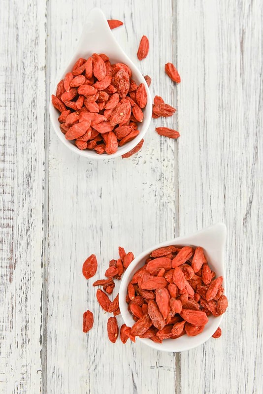 Dried Goji Berries as high detailed close-up shot on a vintage wooden table (selective focus)