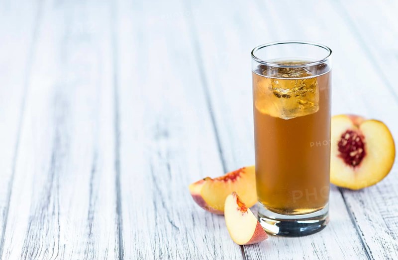 Peach ice tea (selective focus) on an old wooden table (close-up shot)