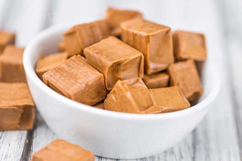 Caramel pieces as high detailed close-up shot on a vintage wooden table (selective focus)