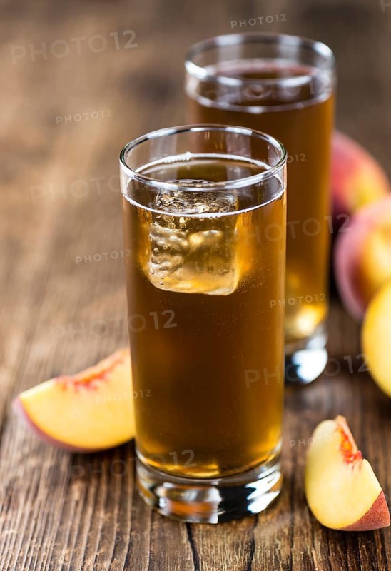 Fresh made peach ice tea (selective focus) on an old wooden table (close-up shot)
