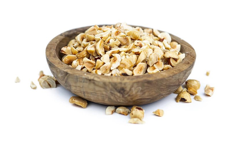 Freshly chopped Hazelnuts as detailed close up shot isolated on white background (selective focus)