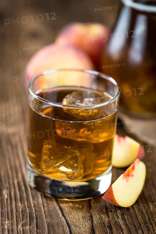 Ice Tea (Peach) on an old wooden table (selective focus, close-up shot)