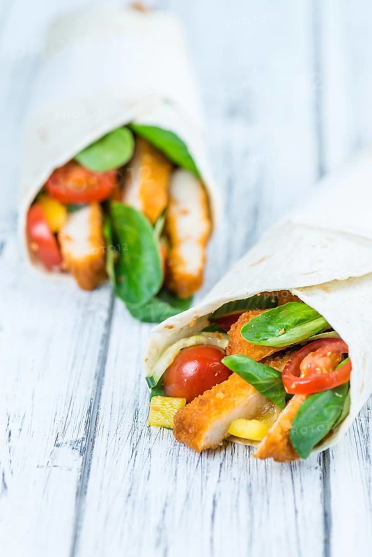 Chicken Wraps on a wooden table as detailed close-up shot (selective focus)