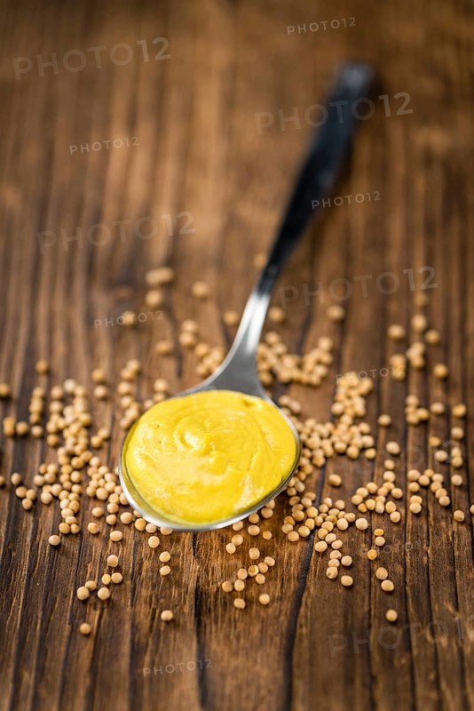 Fresh made Mustard on a vintage background (close-up shot)